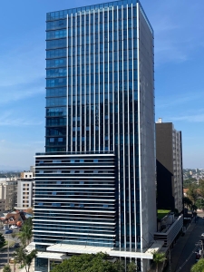 A towering modern skyscraper dominates the urban skyline on a clear day.