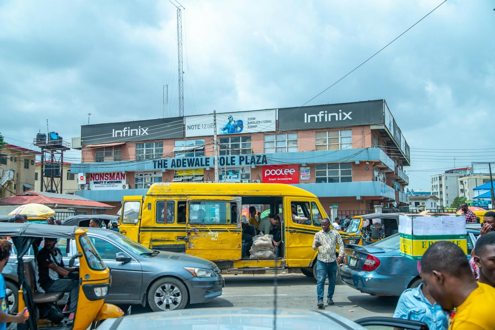 Vibrant urban life in Lagos with traffic and pedestrians by The Adewale Kola Plaza.