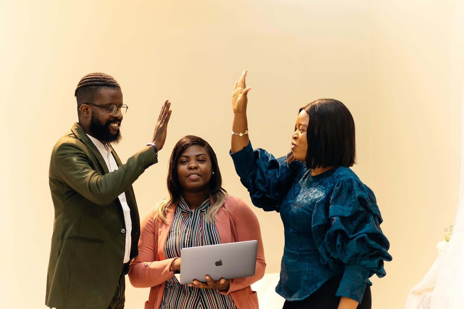 Three colleagues celebrating a successful meeting with high-fives in a Lagos office.