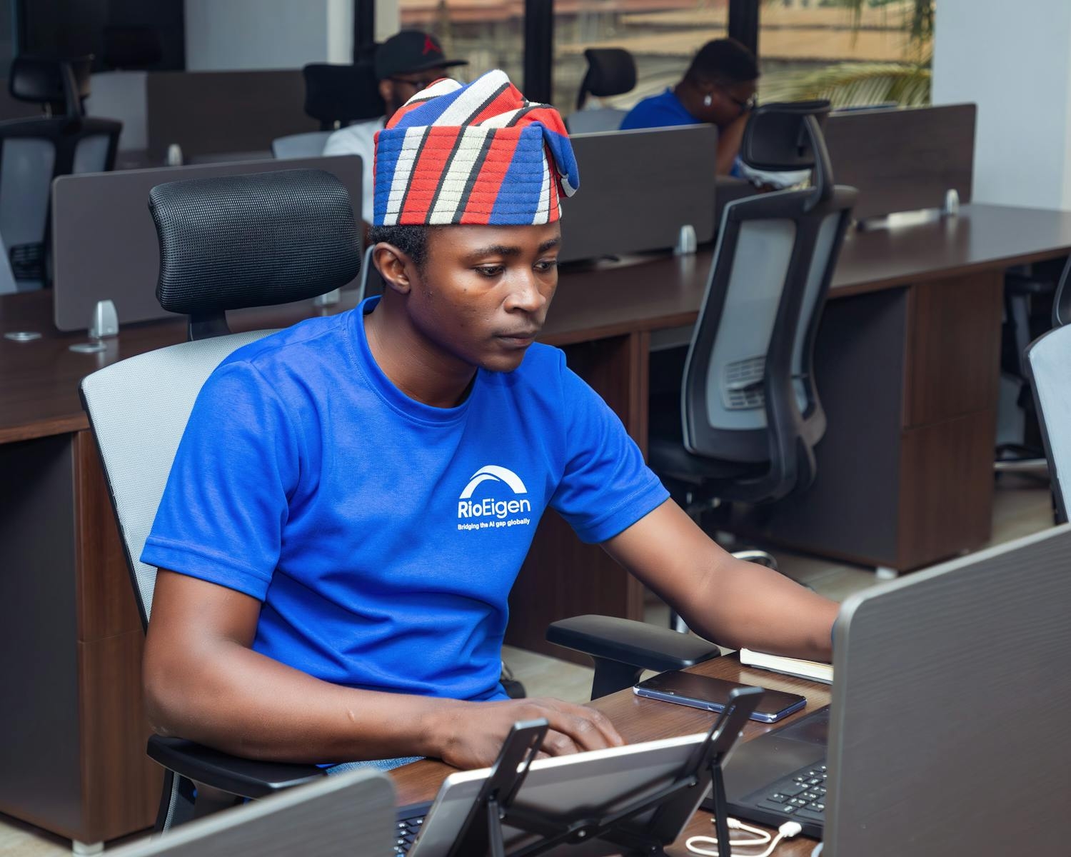 Focused man in traditional hat working at computer in a modern office environment.