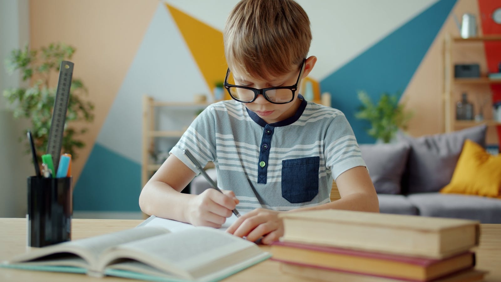 Focused child writing at home with books. Bright, creative learning environment.