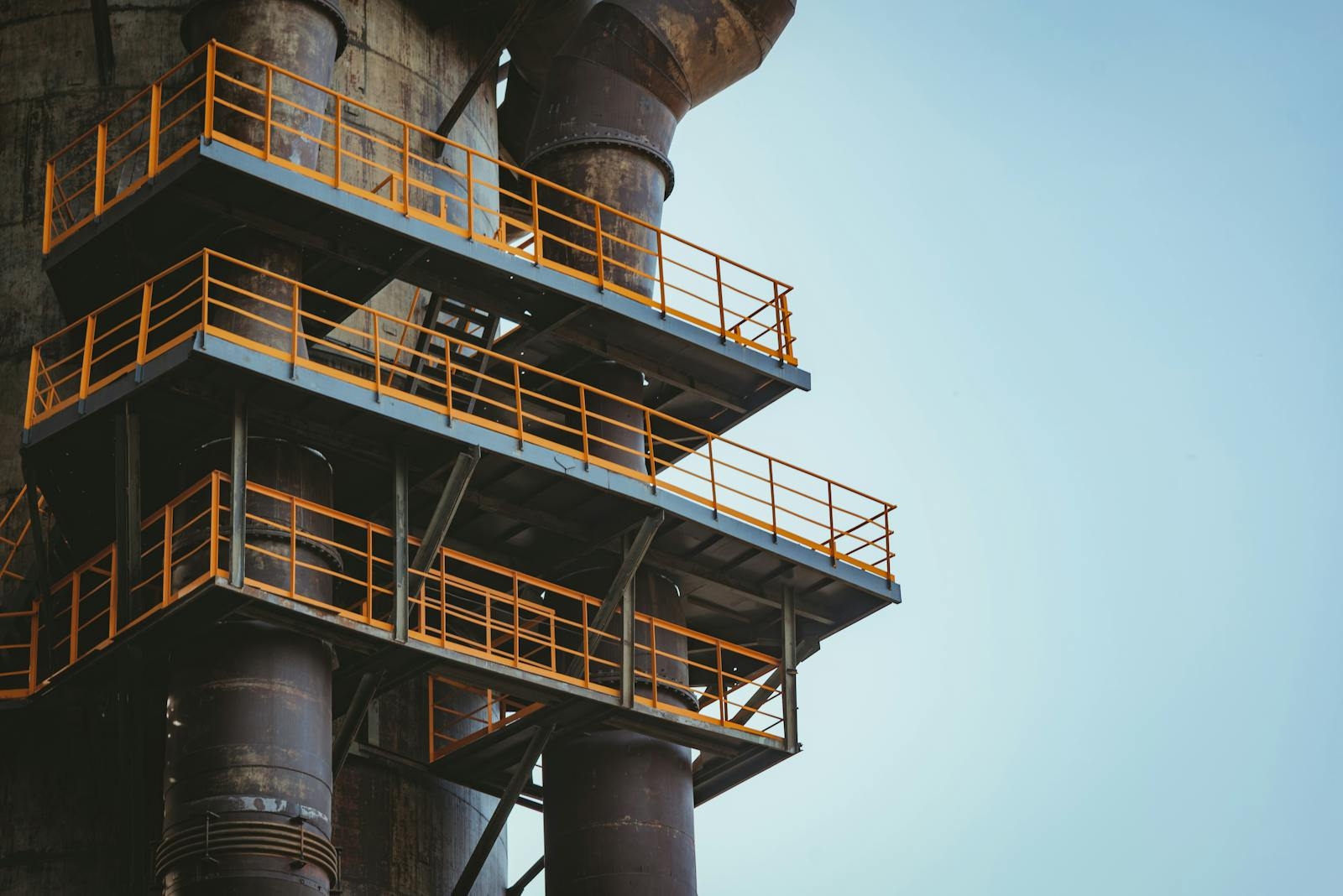 Close-up view of industrial metal balconies and pipes against a clear sky.
