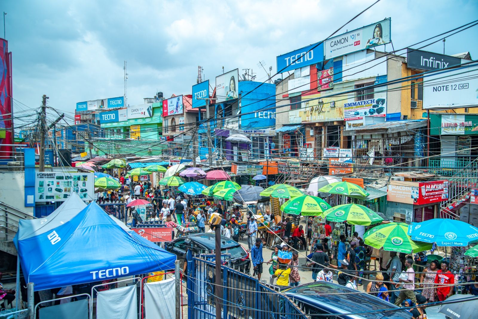 A bustling market with colorful umbrellas and billboards in Lagos, Nigeria.