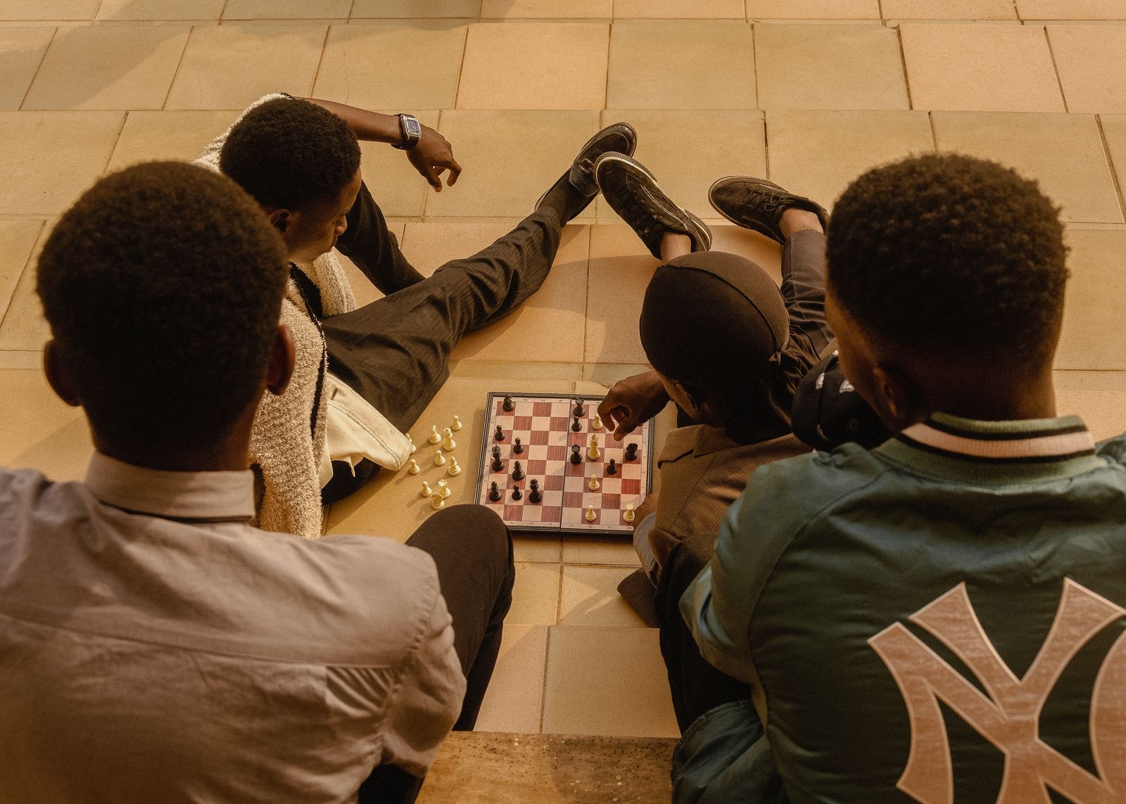 A group of youth engaging in a chess game outdoors in Ado Ekiti, Nigeria.