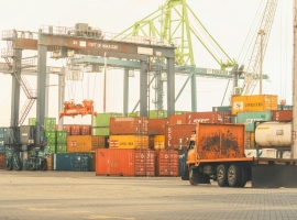 Busy cargo terminal at the Port of Makassar with containers and cranes, vibrant industrial scene.