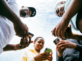 A diverse group of friends using smartphones together on a sunny day in Brussels.