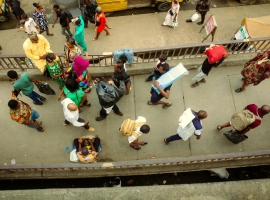 Overhead view of a bustling pedestrian bridge in Lagos, Nigeria with diverse people in vibrant attire.
