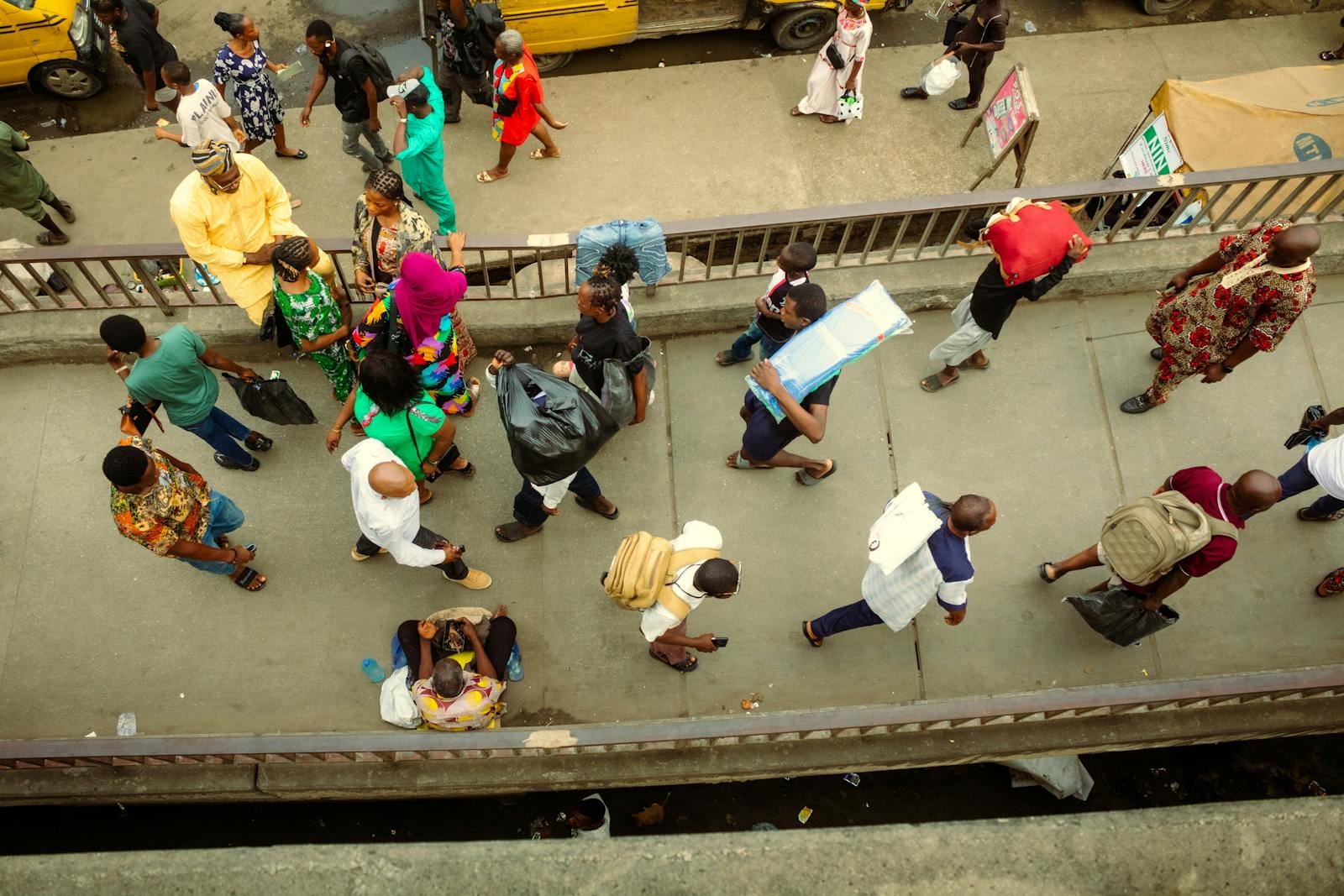 Overhead view of a bustling pedestrian bridge in Lagos, Nigeria with diverse people in vibrant attire.