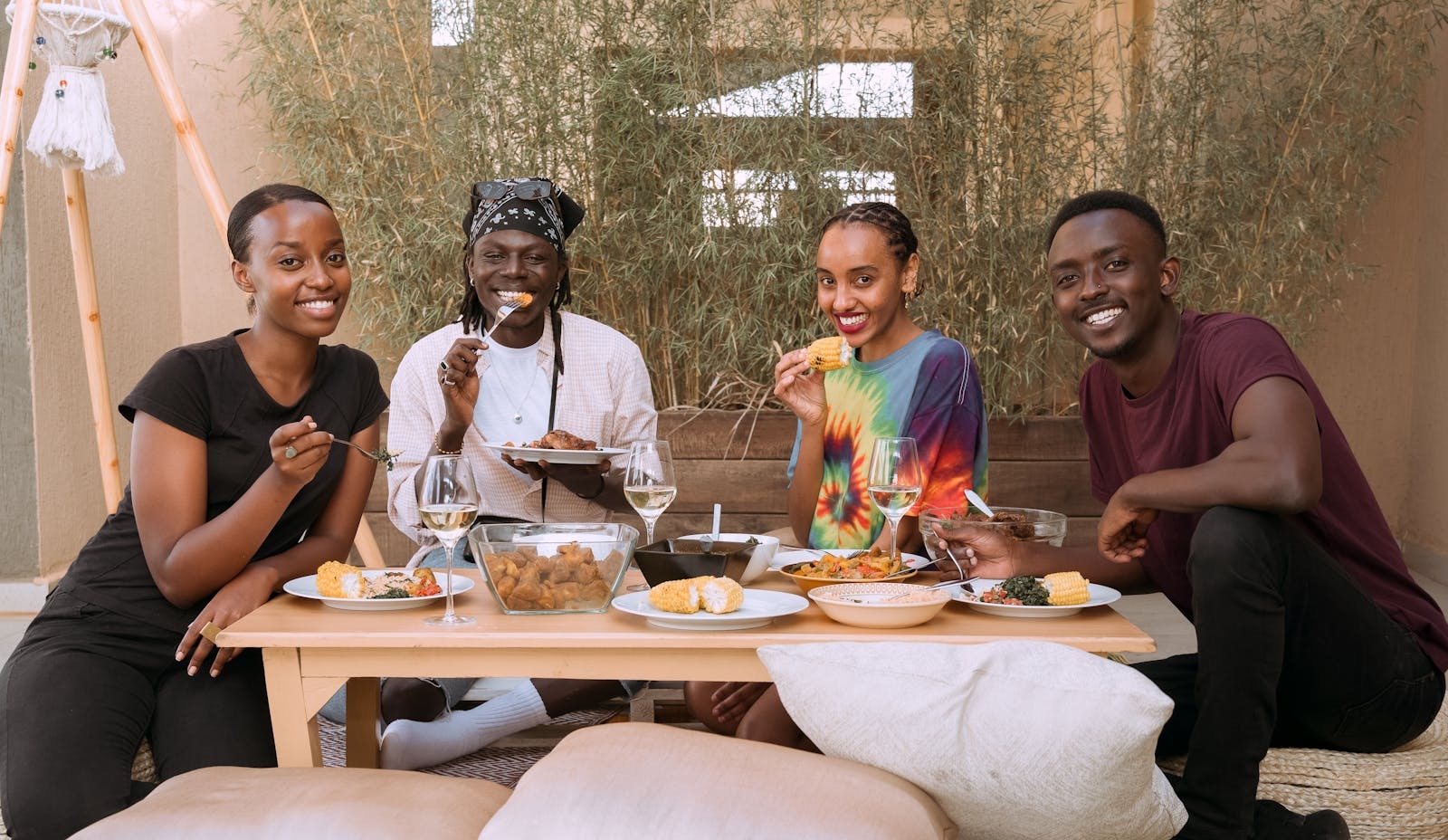 Four friends smiling and enjoying a meal together, exuding joy and togetherness.