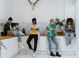 Casual and diverse colleagues using gadgets in a modern office kitchen area.