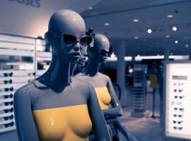 Close-up of stylish mannequins wearing sunglasses and yellow tops in a chic store setting.