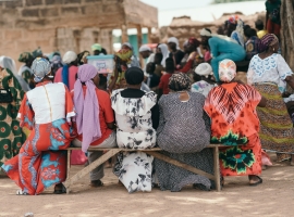 Women in colorful clothes sitting on a bench outdoors.